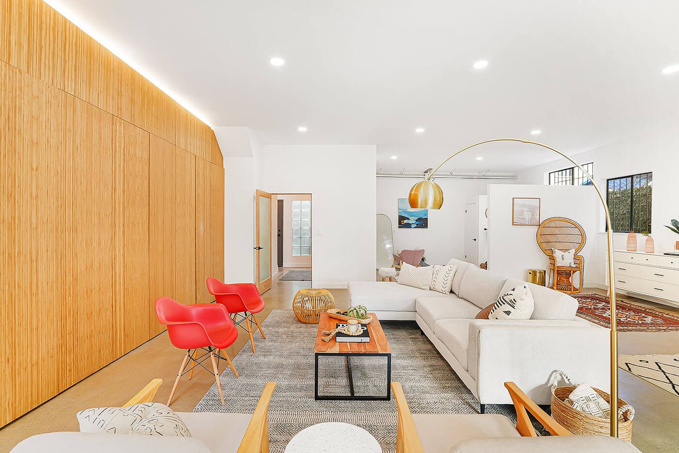 A white living room with red chairs, photographed by a member studio